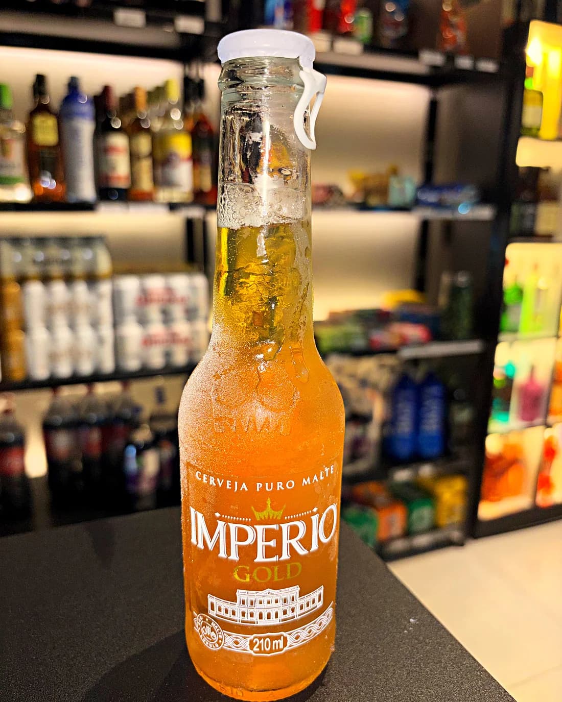 Garrafa gelada de Império Gold 210 ml, coberta de gelo, no balcão da loja