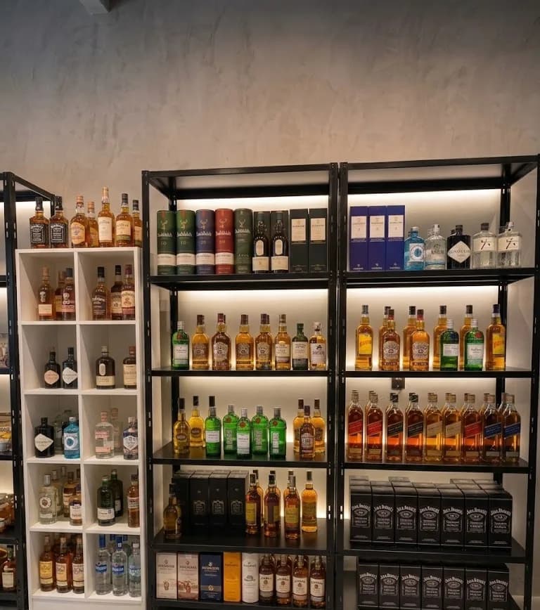 Prateleiras iluminadas com whiskies, gins e outros destilados